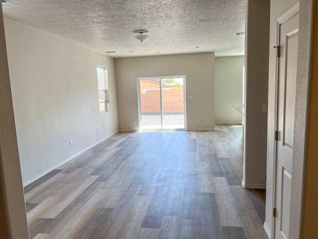 unfurnished room with light wood-type flooring and a textured ceiling