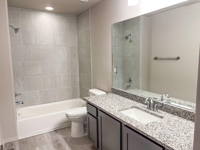 full bathroom with wood-type flooring, tiled shower / bath combo, vanity, and toilet