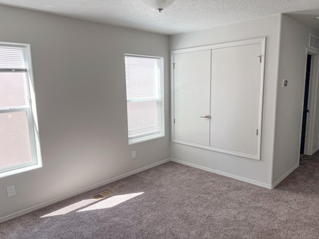 unfurnished bedroom with light carpet, a closet, and a textured ceiling