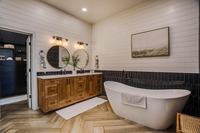 full bathroom with double vanity, visible vents, a freestanding bath, a sink, and recessed lighting