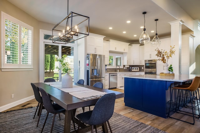 dining room with recessed lighting, wood finished floors, decorative columns, and baseboards