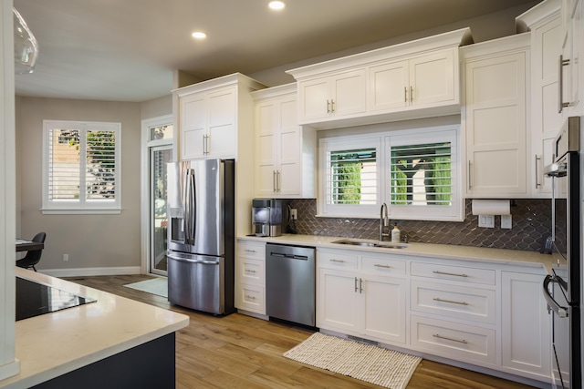 kitchen featuring light countertops, appliances with stainless steel finishes, a sink, and white cabinetry