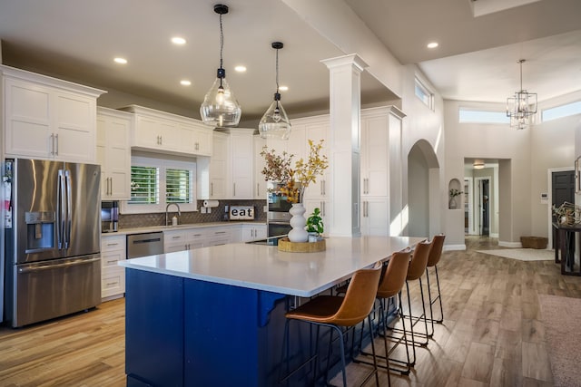 kitchen featuring light wood-type flooring, a spacious island, white cabinetry, and appliances with stainless steel finishes