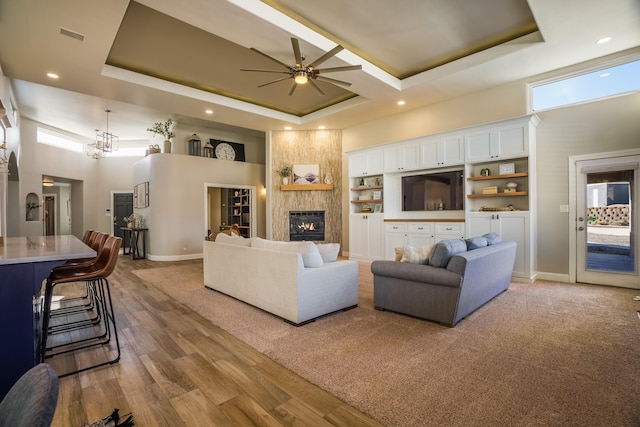 living area with a tray ceiling, a large fireplace, and a high ceiling