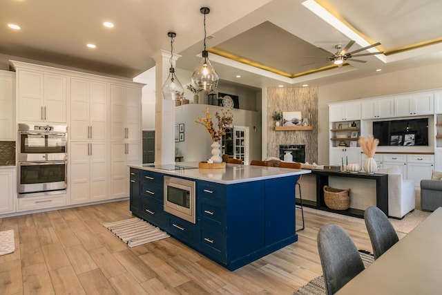 kitchen with open floor plan, blue cabinetry, appliances with stainless steel finishes, and white cabinetry