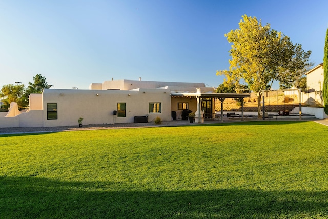 back of property featuring stucco siding, a patio, and a lawn