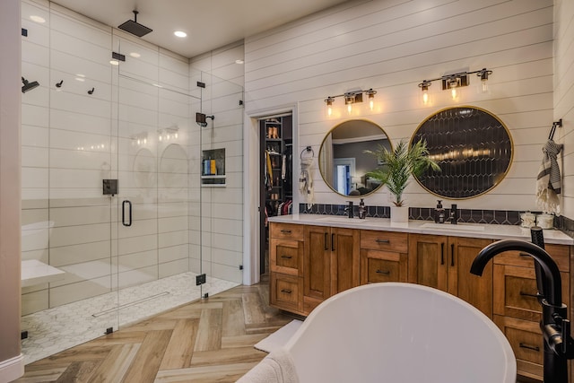 bathroom with double vanity, a stall shower, a sink, and a soaking tub