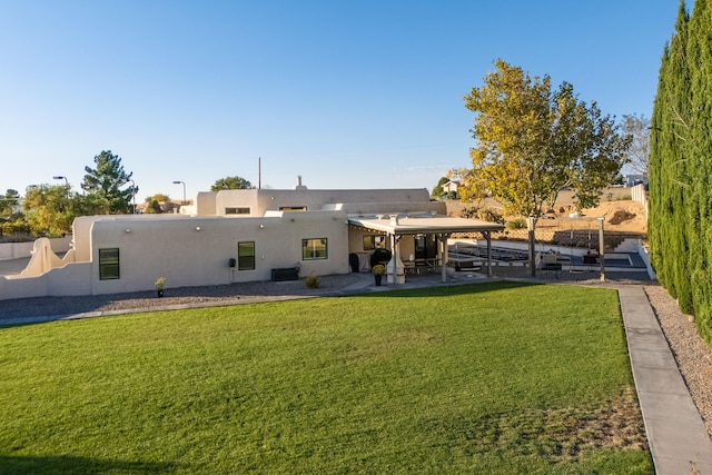 back of property with stucco siding, a lawn, fence, and a patio