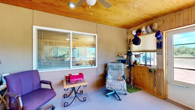 living area featuring wooden ceiling, wooden walls, and ceiling fan