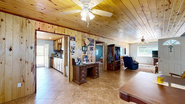 interior space with wooden ceiling, light tile patterned flooring, wooden walls, and ceiling fan