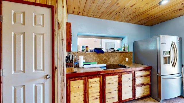 kitchen with stainless steel fridge, black electric stovetop, backsplash, tile counters, and wooden ceiling