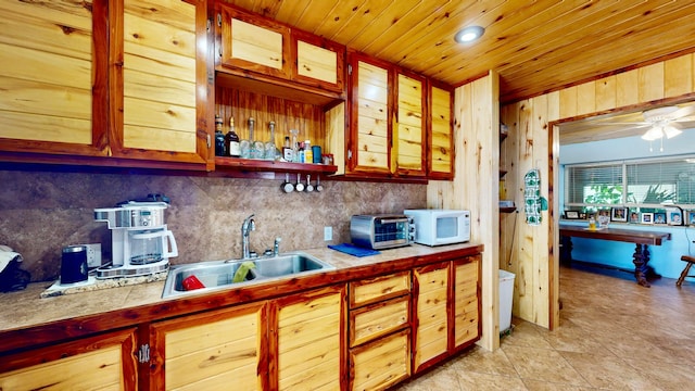 kitchen with wood ceiling, sink, wood walls, light tile patterned floors, and ceiling fan