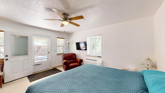 bedroom featuring a textured ceiling, light hardwood / wood-style floors, ceiling fan, and a wall mounted air conditioner