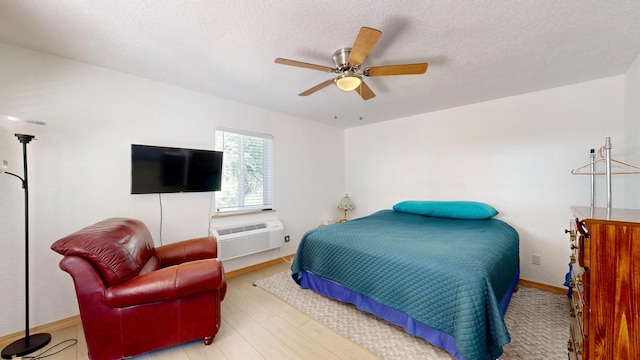 bedroom with a textured ceiling, light hardwood / wood-style floors, and ceiling fan