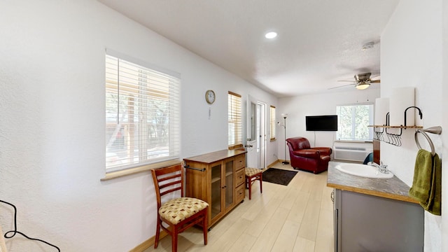 living room featuring ceiling fan, light wood-type flooring, and sink