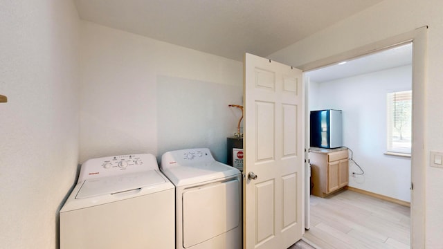 clothes washing area with light wood-type flooring, water heater, and separate washer and dryer