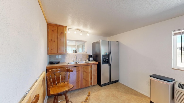 kitchen with a textured ceiling, stainless steel fridge, sink, and tasteful backsplash