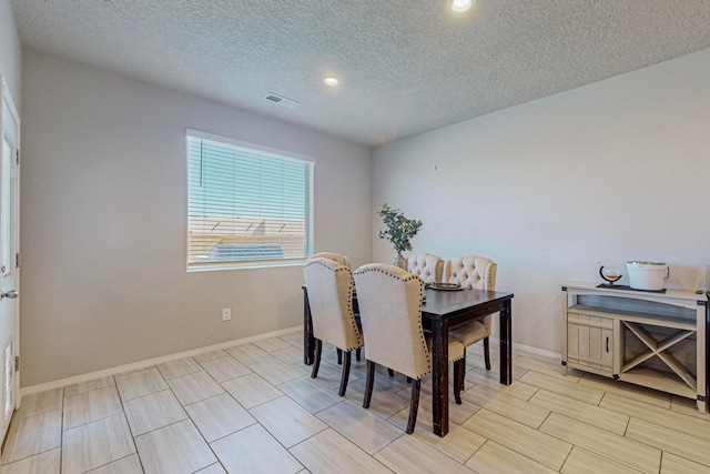 dining room with a textured ceiling and light hardwood / wood-style floors