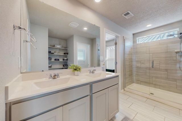 bathroom featuring walk in shower, vanity, and a textured ceiling