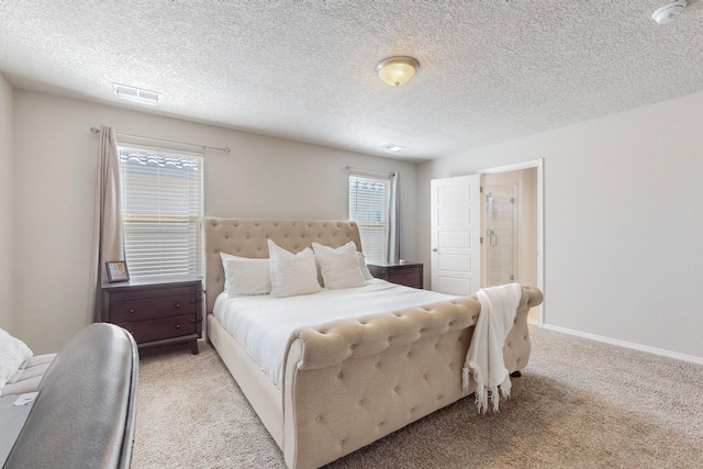 bedroom with light colored carpet, ensuite bathroom, and a textured ceiling