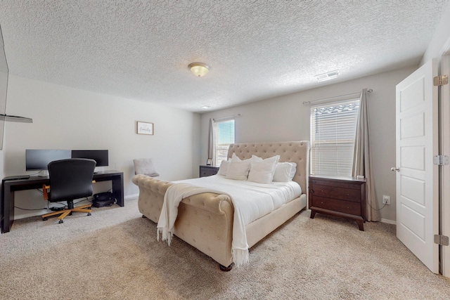 bedroom with light colored carpet and a textured ceiling