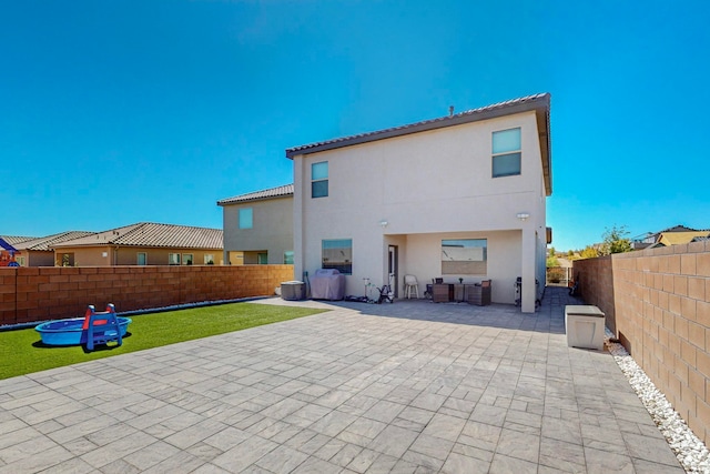 back of property with a lawn and a patio