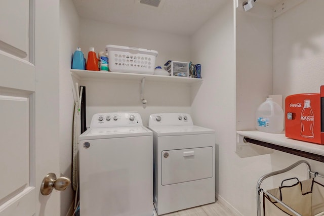 laundry room with light wood-type flooring and washer and clothes dryer