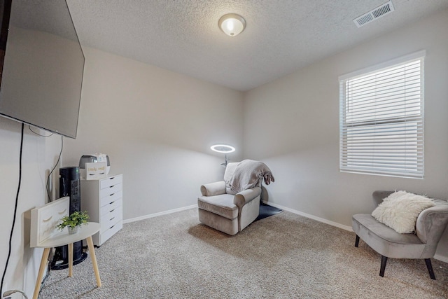 living area with a textured ceiling and light colored carpet