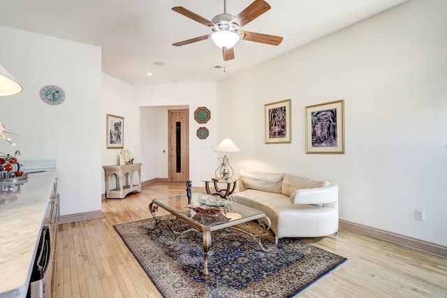 living room with light hardwood / wood-style floors, sink, and ceiling fan