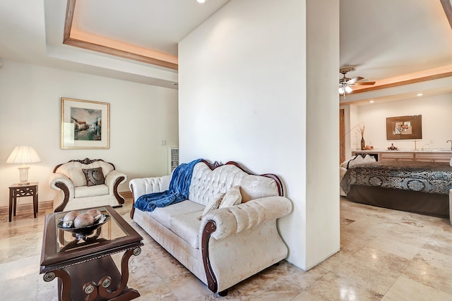 living room with ceiling fan and a tray ceiling