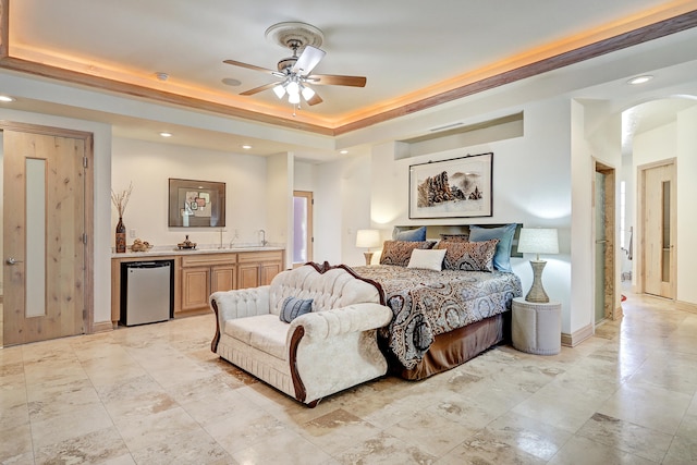 bedroom with ceiling fan, indoor wet bar, and a raised ceiling