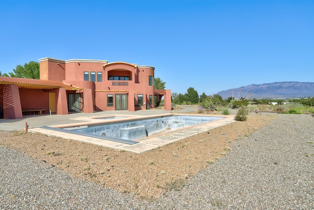 view of pool featuring a mountain view, a jacuzzi, and a patio area