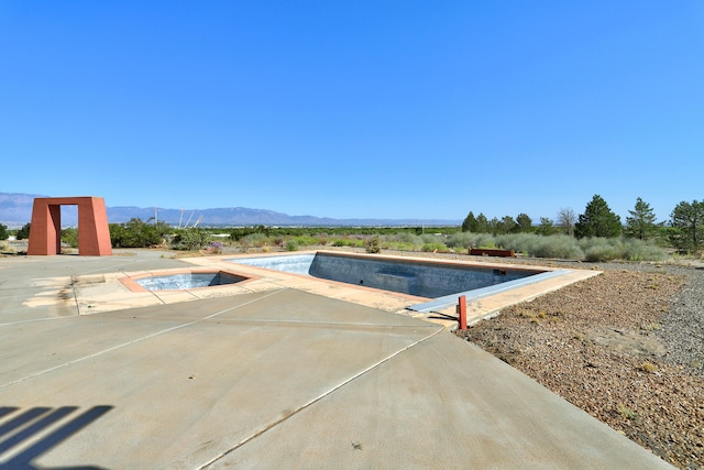 view of swimming pool with a mountain view, an in ground hot tub, and a patio area