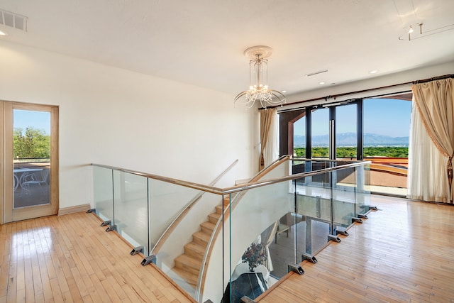 staircase with an inviting chandelier, a mountain view, and hardwood / wood-style flooring