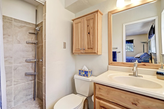 bathroom with tiled shower, vanity, and toilet