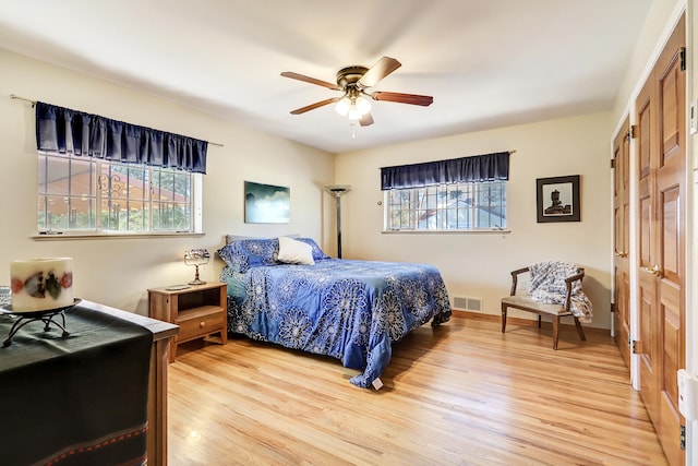 bedroom featuring ceiling fan, light hardwood / wood-style floors, and multiple windows