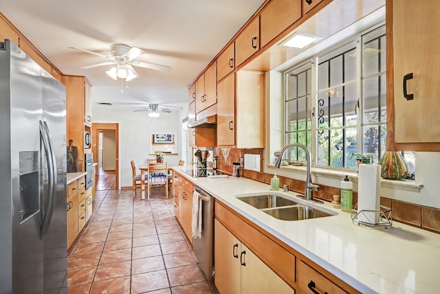 kitchen featuring appliances with stainless steel finishes, backsplash, light tile patterned floors, ceiling fan, and sink