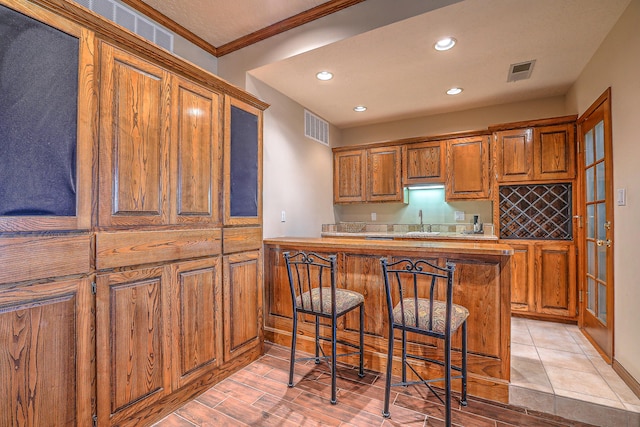 kitchen with ornamental molding, a breakfast bar area, sink, and light hardwood / wood-style floors