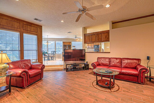 living room with ceiling fan, light hardwood / wood-style floors, and a textured ceiling