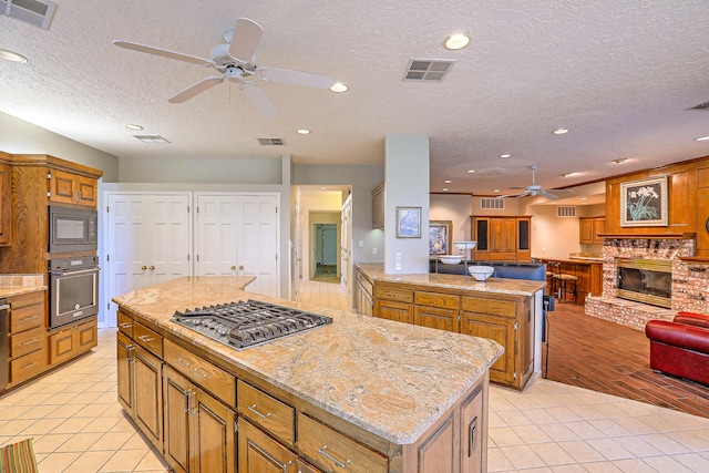 kitchen featuring a textured ceiling, stainless steel appliances, light wood-type flooring, and a kitchen island