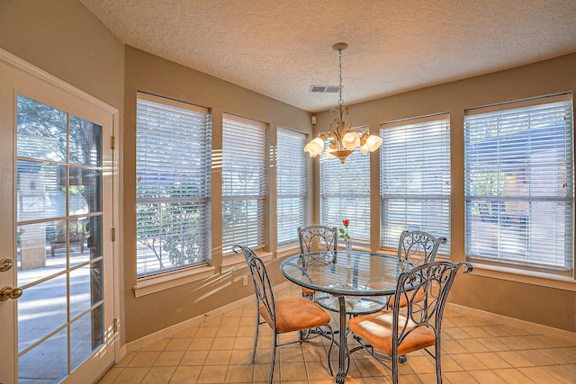 tiled dining room featuring an inviting chandelier and a textured ceiling