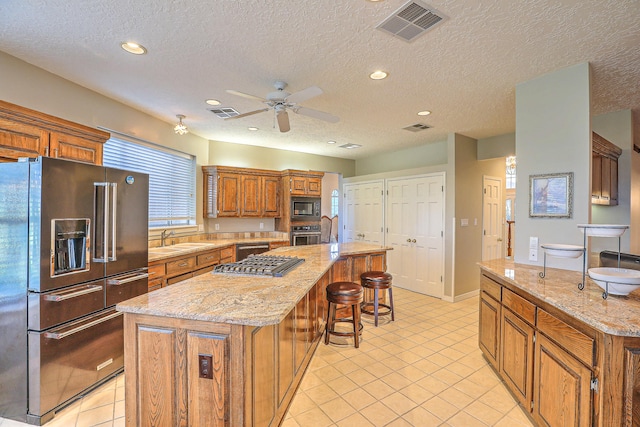 kitchen featuring an island with sink, appliances with stainless steel finishes, and a textured ceiling