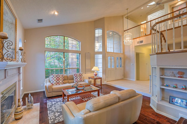 living room with wood-type flooring, high vaulted ceiling, an inviting chandelier, and a textured ceiling