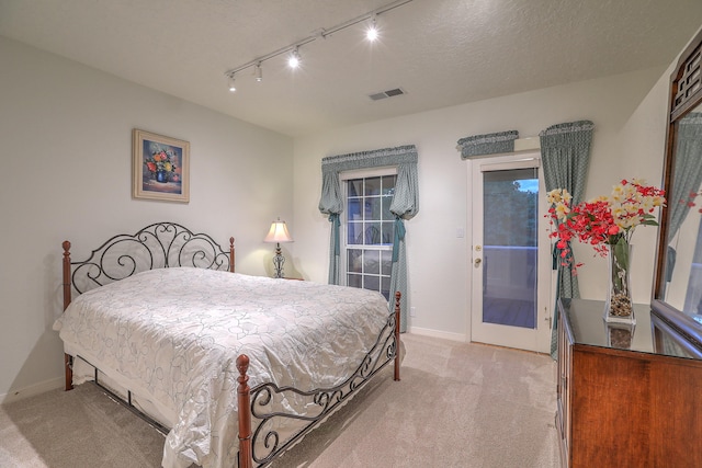 carpeted bedroom with a textured ceiling and track lighting