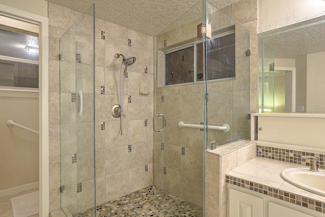 bathroom featuring vanity, a shower with shower door, and a textured ceiling