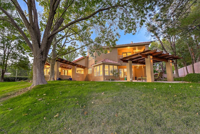 rear view of property with a pergola, a lawn, and a patio area