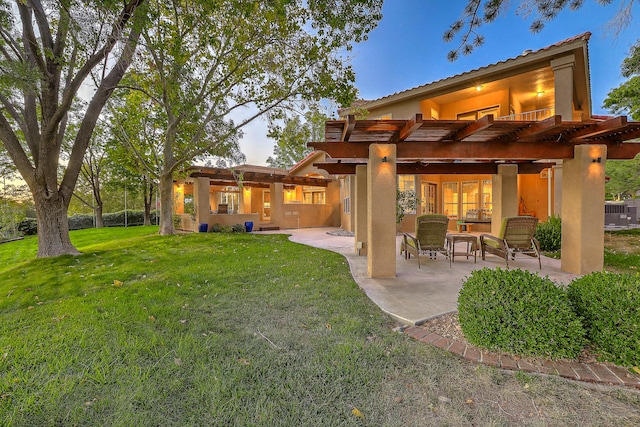 rear view of house featuring a yard, a pergola, and a patio area