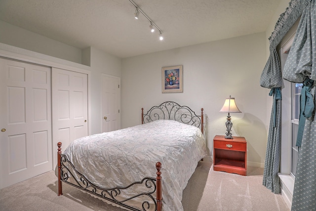 carpeted bedroom featuring track lighting, a closet, and a textured ceiling