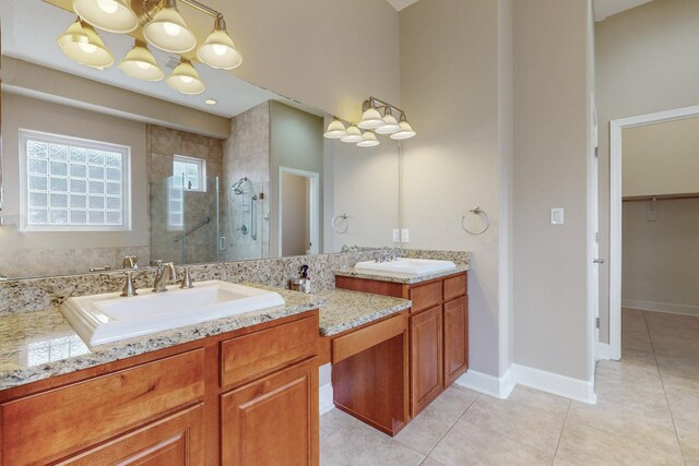 bathroom with an inviting chandelier, vanity, a shower with shower door, and tile patterned flooring