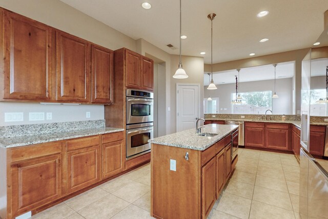 370 Zuni River Cir SW, Los Lunas, NM 87031 - kitchen featuring stainless steel appliances, brown cabinets, recessed lighting, light tile patterned flooring, and light stone countertops